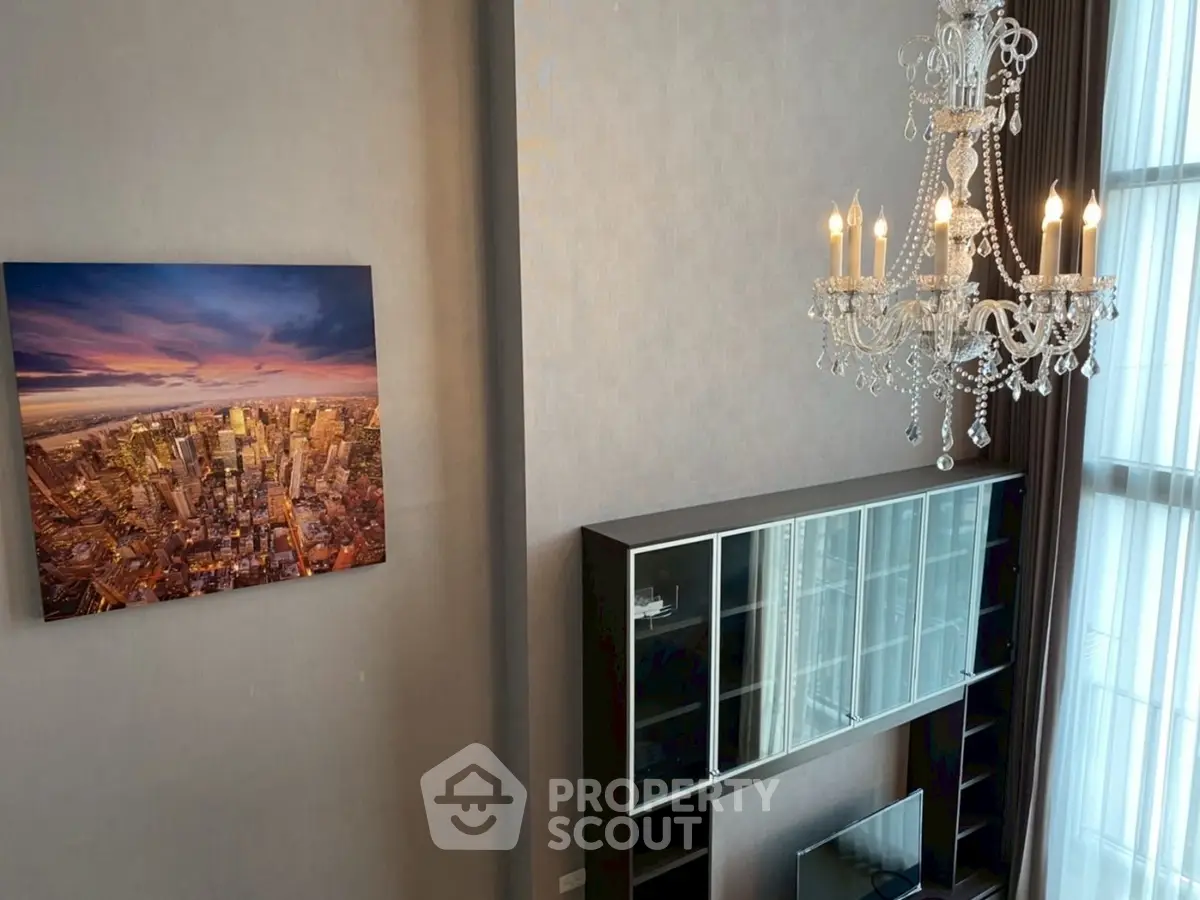 Luxurious living room with high ceiling, elegant chandelier, and cityscape artwork, perfect for modern urban living.