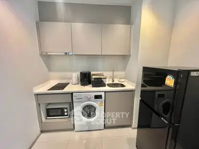 Modern compact kitchen with appliances including washing machine and fridge in sleek design.