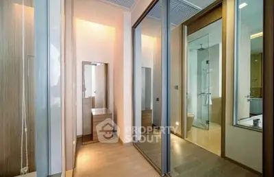 Spacious modern bedroom with mirrored closets and ensuite bathroom in luxury apartment.