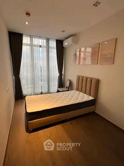 Modern bedroom with large window and stylish decor in a high-rise apartment.