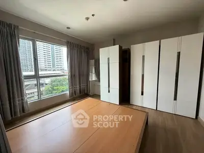 Spacious bedroom with large windows and modern wardrobe in urban apartment