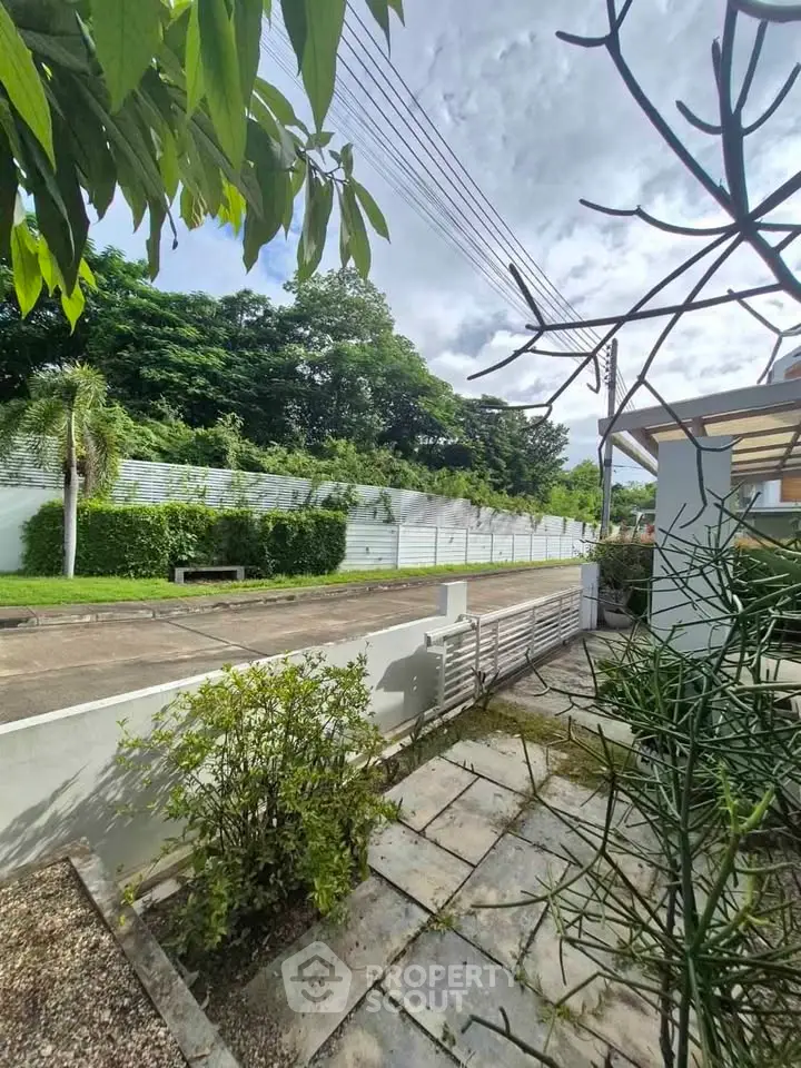 Charming residential garden with lush greenery and paved walkway, perfect for outdoor relaxation.