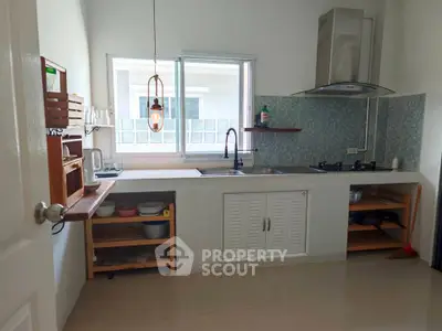Modern kitchen with gas stove and open shelving, featuring sleek design and natural light.