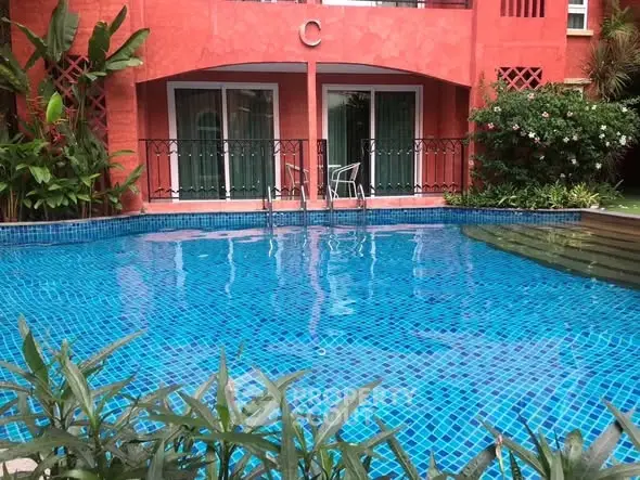 Stunning poolside view with vibrant red building backdrop and lush greenery.