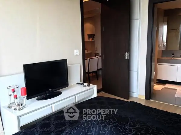 Modern bedroom with TV and view into stylish bathroom and dining area