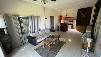 Spacious living room with cozy seating and open kitchen layout, perfect for modern living.