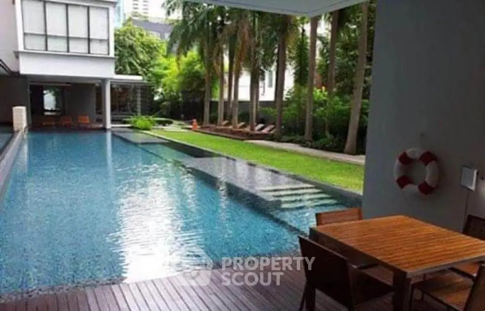 Luxurious poolside area with lush greenery and modern seating, perfect for relaxation and leisure.