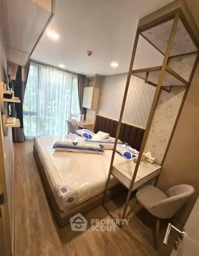 Modern bedroom with large window and stylish decor, featuring a cozy bed and elegant furnishings.