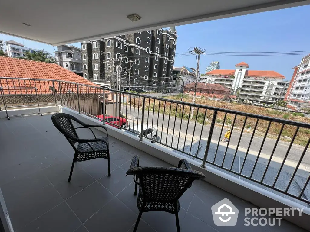 Spacious balcony with modern wicker chairs offering an urban view, ideal for relaxation and outdoor entertaining in a contemporary residence.