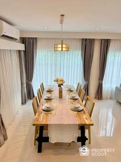 Elegant dining room with wooden table, modern lighting, and floor-to-ceiling curtains.