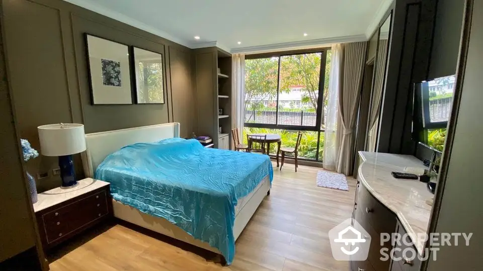 Spacious bedroom with large window and garden view, featuring elegant decor and modern furniture.