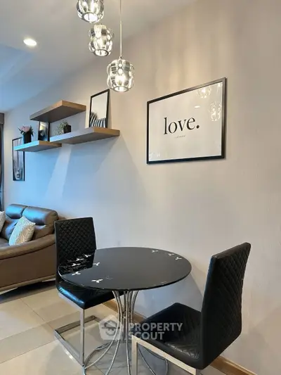 Modern dining area with stylish black chairs and round table, elegant wall decor, and cozy living room view.