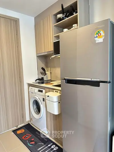 Modern kitchen with fridge, washing machine, and sleek cabinetry