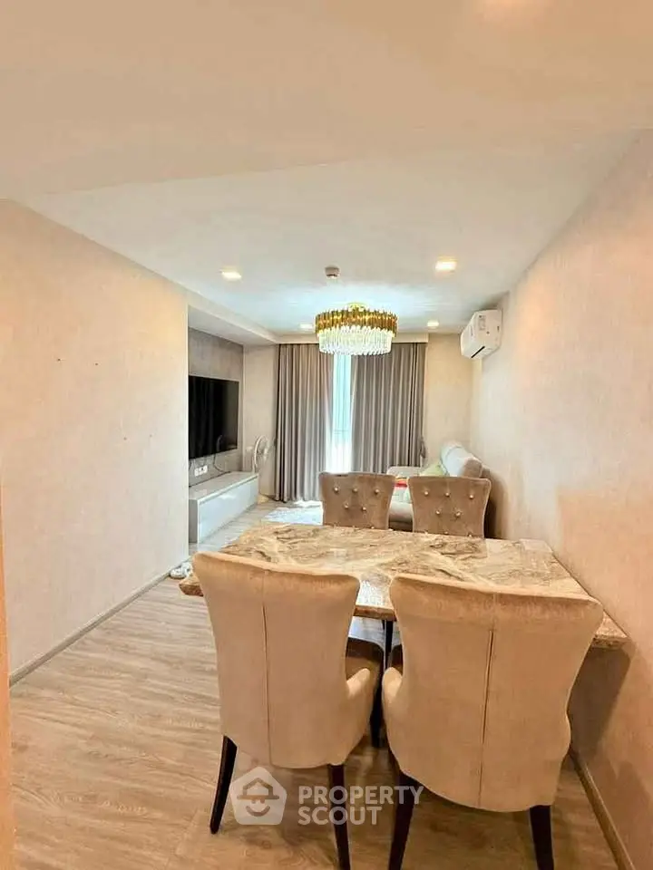 Elegant living room with modern decor, featuring a stylish dining area and luxurious chandelier.