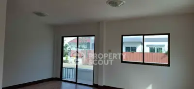 Spacious living room with large windows and sliding glass door, offering ample natural light and outdoor view.