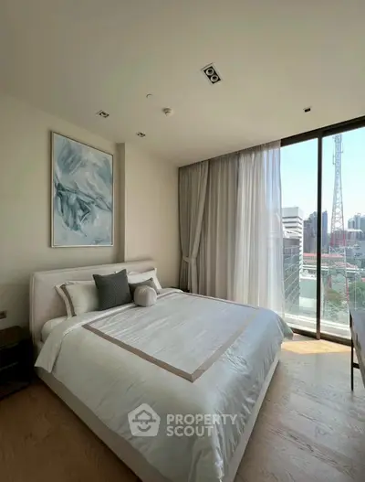 Modern bedroom with large window and city view, featuring elegant decor and natural light.