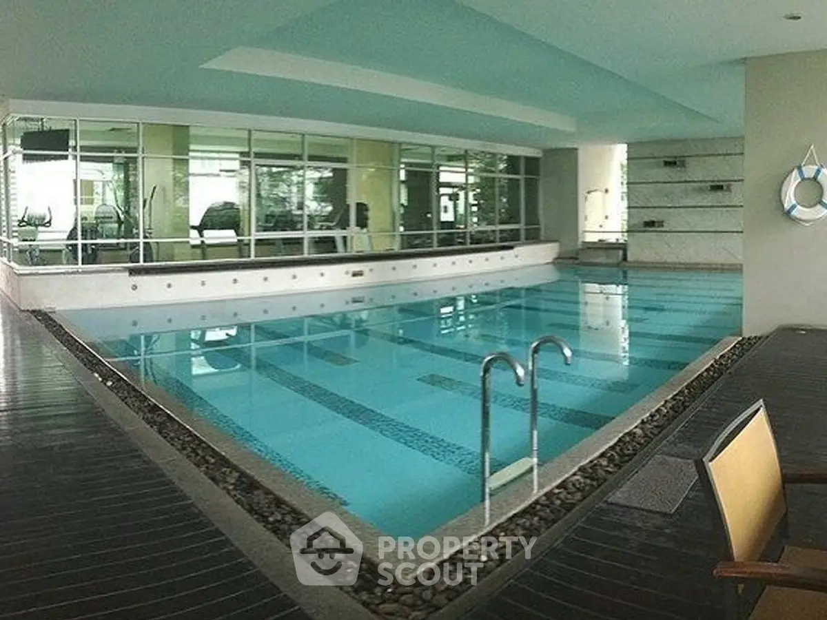 Luxurious indoor swimming pool with modern design and gym view, perfect for relaxation and fitness.