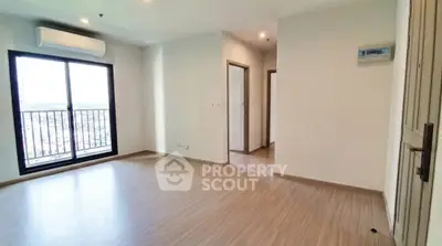 Spacious empty living room with large window and wooden flooring in modern apartment.