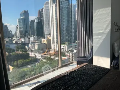 Luxurious bedroom with stunning cityscape view through large window, perfect for urban living.