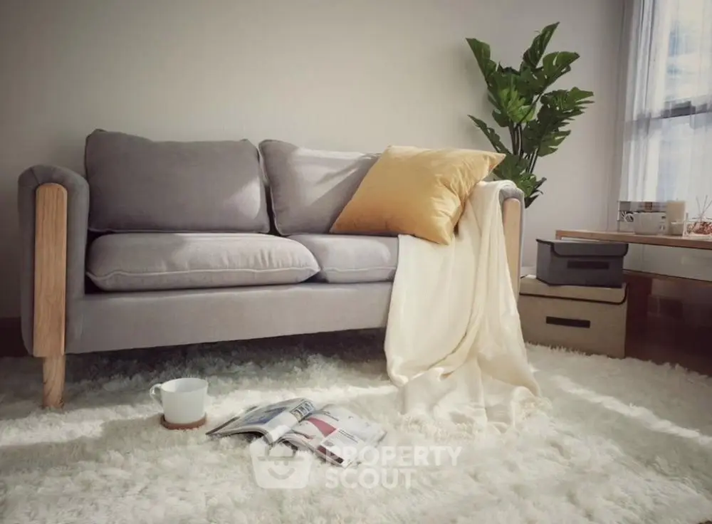 Cozy living room with plush sofa, soft rug, and natural light, perfect for relaxation.