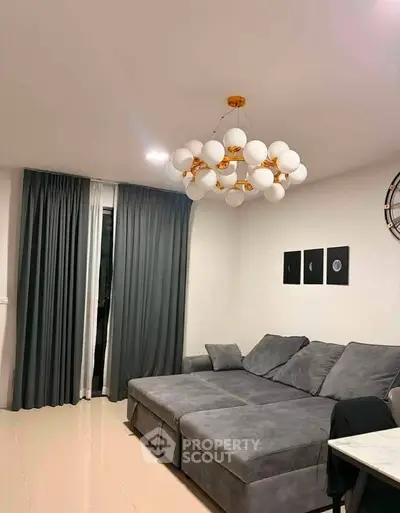 Modern living room with elegant chandelier and plush gray sofa