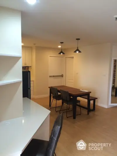 Spacious dining area with modern lighting and wooden flooring in a stylish apartment.