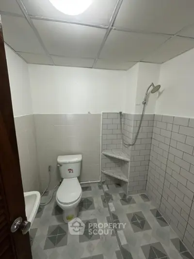 Spacious bathroom with modern shower and tiled walls, perfect for a contemporary home.