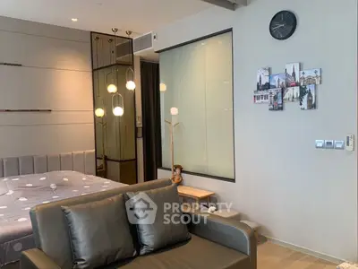 Modern bedroom with stylish decor and cozy seating area, featuring elegant lighting and wall art.
