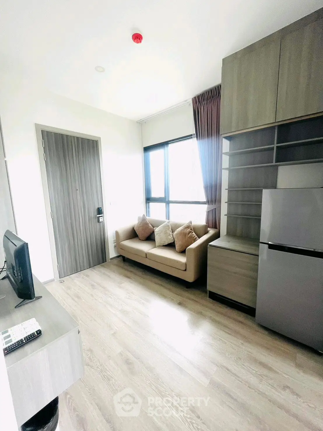 Modern living room with sleek furniture and natural light, featuring a cozy sofa and a compact kitchen area.