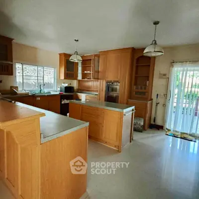 Spacious kitchen with wooden cabinets and modern appliances, featuring an open layout and ample natural light.
