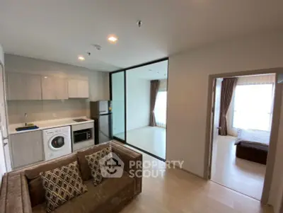 Modern open-plan apartment with kitchen, living area, and bedroom featuring large windows.