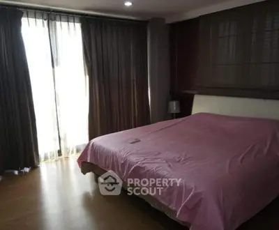 Spacious bedroom with large window and elegant curtains, featuring a cozy bed with pink bedding.