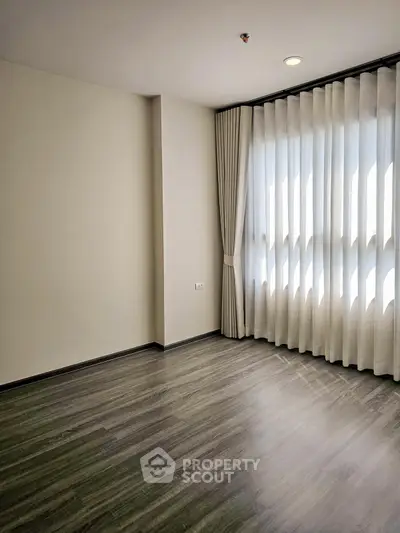 Spacious empty room with elegant floor-to-ceiling curtains and sleek flooring, perfect for customization.