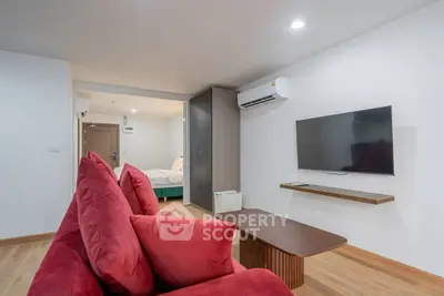 Modern living room with red sofa, wall-mounted TV, and air conditioning in a stylish apartment.