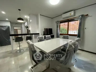 Modern dining area with sleek white table and stylish chairs in open-concept kitchen.