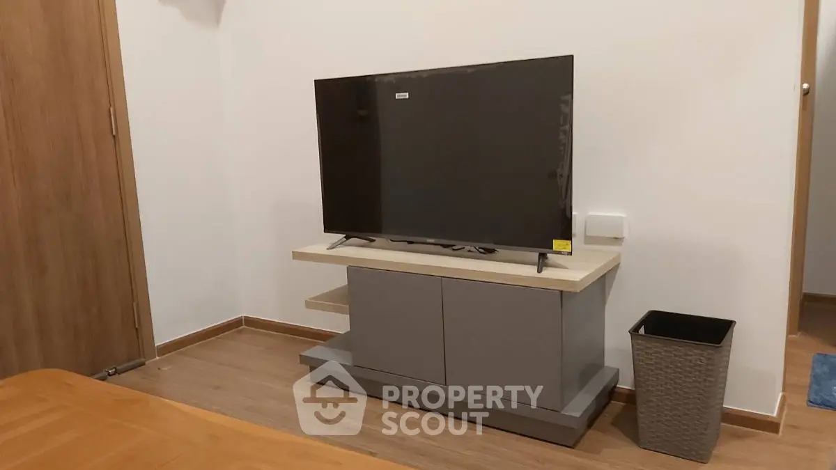 Modern living room with sleek TV stand and flat-screen TV, wooden flooring, and minimalist decor.