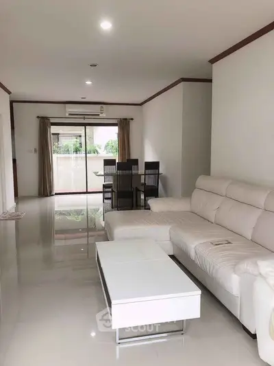 Spacious modern living room with sleek white sofa and dining area