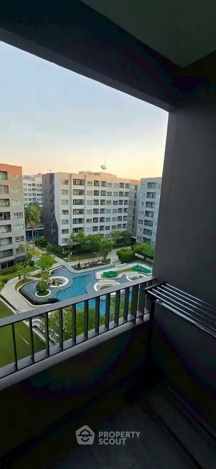 Stunning view from balcony overlooking modern apartment complex with pool and lush greenery.