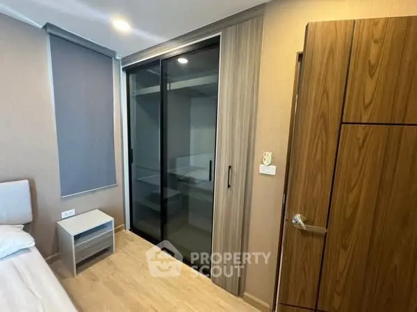 Modern bedroom with sleek sliding closet doors and wooden accents.