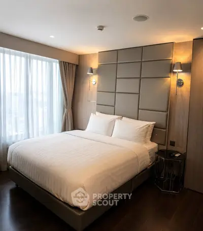 Luxurious bedroom with modern decor and large window offering city views.