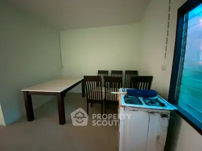 Cozy dining area with table, chairs, and compact gas stove in a minimalist setting.