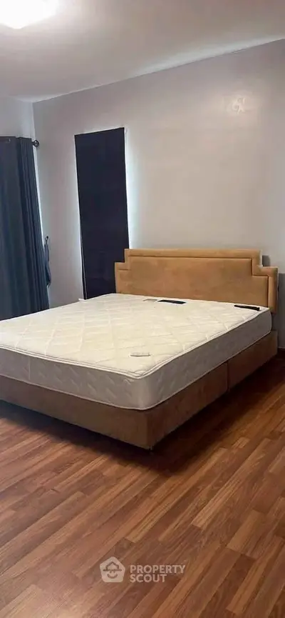 Spacious bedroom with elegant wooden flooring and modern bed frame, perfect for a cozy retreat.