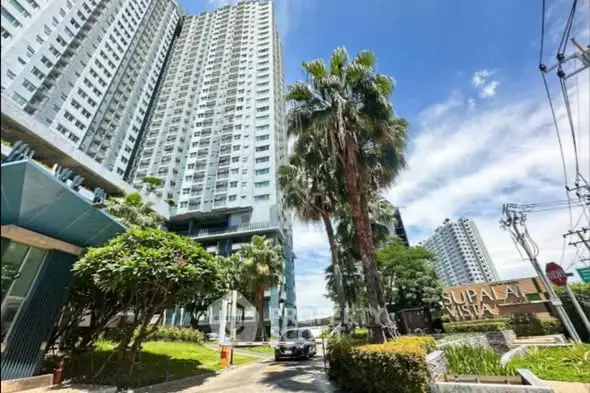 Stunning high-rise residential building with lush landscaping and clear blue sky.