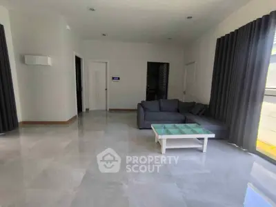 Spacious modern living room with sleek tile flooring and stylish gray sofa