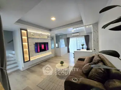 Modern living room with stylish decor and open layout, featuring a cozy sofa and sleek entertainment center.