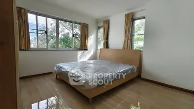 Spacious bedroom with large windows and natural light in modern apartment.