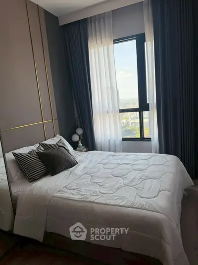 Modern bedroom with stylish decor and large window offering city views, perfect for urban living.