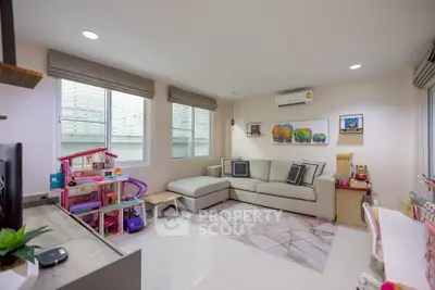 Spacious living room with modern decor and ample natural light, featuring a cozy sectional sofa and children's play area.