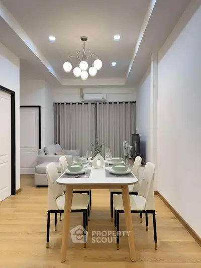 Modern dining area with stylish lighting and cozy living room in open layout apartment.