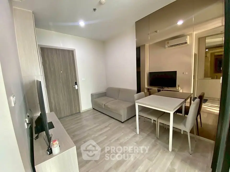 Modern living room with sleek furniture and mirrored wall in a cozy apartment.